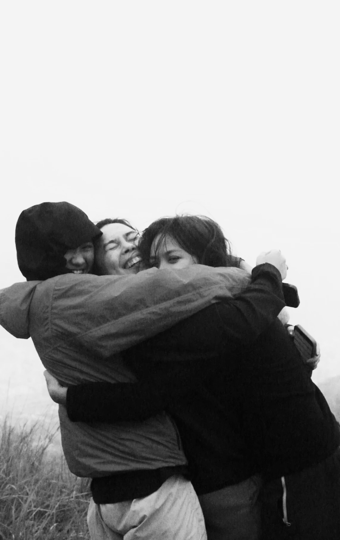 Ч/б кадр: трійка на засніженому схилі над хмарами